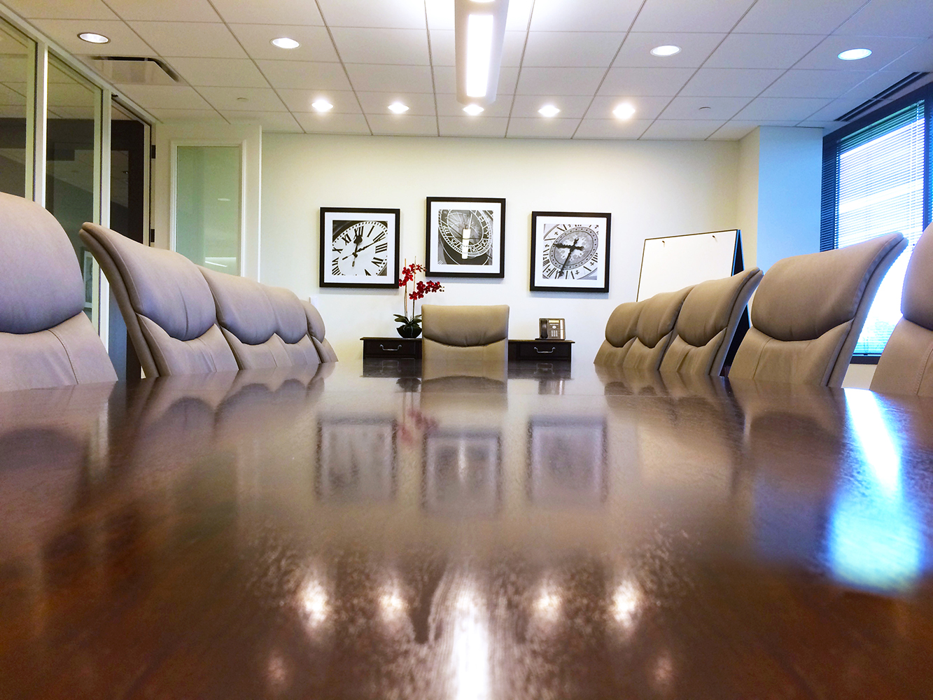 View of board room from table top of chairs, table and back wall with artwork hanging Architectural Photography