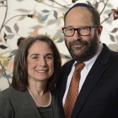 Rabbi and wife portrait in front of decorative artwork